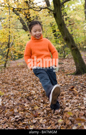 Mädchen treten verlässt, wie sie in einem Wald im Herbst geht. Stockfoto
