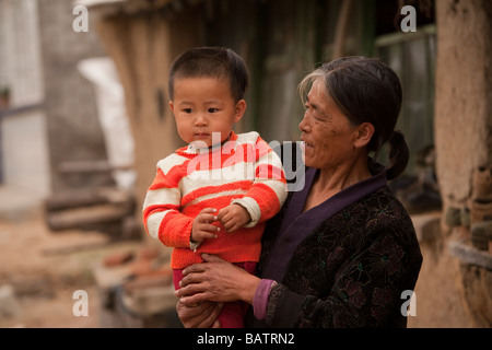 Changchun, Provinz Jilin, China.  Ein kleiner Junge in den Armen seiner Mutter außerhalb der eigenen Wohnung. Stockfoto