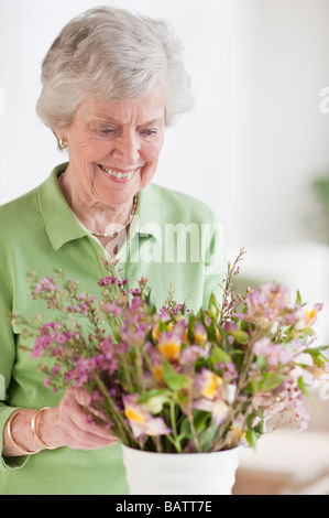 Ältere Frau Einstellung Blumen in vase Stockfoto