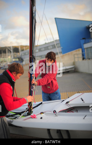 zwei junge Männer, die Vorbereitung zu gehen, Segeln am Weymouth und Portland Sailing Academy in Dorset. Stockfoto