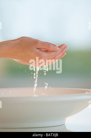 Wasser tropft aus der hohlen Hand über Schüssel Stockfoto