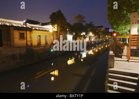 Traditionelle Gebäude und Cafés entlang Canal in der Abenddämmerung, Suzhou, China Stockfoto