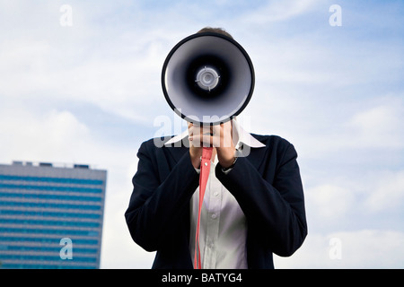 Porträt des jungen Geschäftsfrau versteckt hinter Megaphon Stockfoto