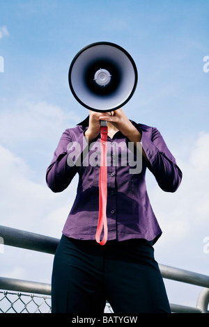 Porträt des jungen Geschäftsfrau versteckt hinter Megaphon Stockfoto