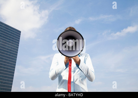 Porträt des jungen Geschäftsfrau versteckt hinter Megaphon Stockfoto