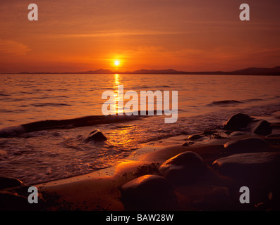 RED SUNSET ACROSS TREMADOG Bucht Lleyn Halbinsel vom Strand mit nassen Felsen und Sand im Vordergrund auf Westküste North Wales UK Stockfoto