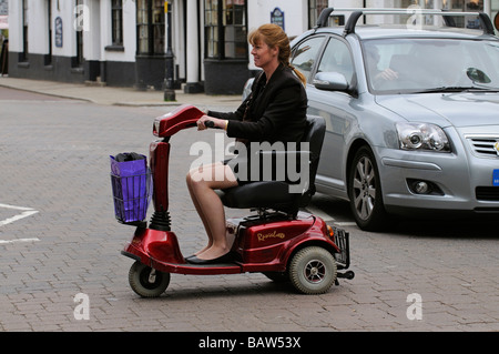 Frau sitzend auf einem Rascal Mobilität Scooter kreuzt die Straße an einem Fußgängerüberweg Stockfoto