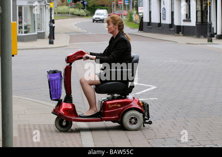 Frau sitzend auf einem Rascal Mobilität Scooter kreuzt die Straße an einem Fußgängerüberweg Stockfoto