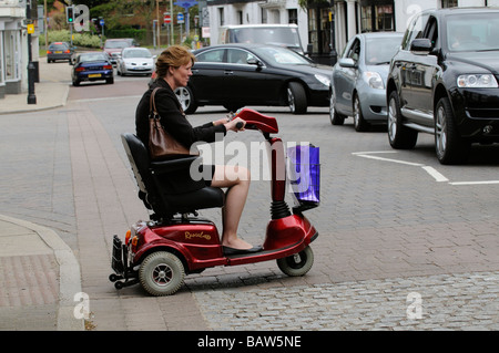 Frau sitzend auf einem Rascal Mobilität Scooter kreuzt die Straße an einem Fußgängerüberweg Stockfoto