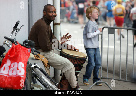 Schlagzeuger Mann Musiker schwarze Trommeln sitzen am Rotterdamer Straße Stadtmarathon machen Lärm Musik Rhythmus Spaß Läufer laufen Stockfoto