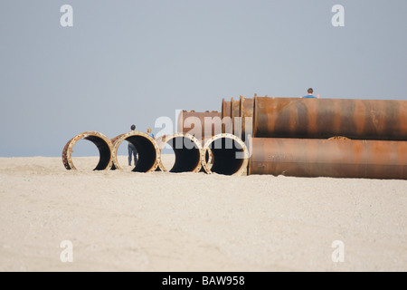 Menschen zu Fuß auf riesigen Stahlrohre Pipeline im Sandstrand unter blauem Himmel Hoek Van Holland Niederlande Stockfoto