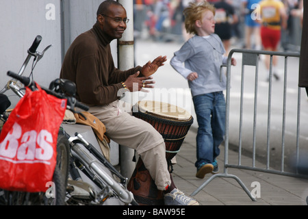 Schlagzeuger Mann Musiker schwarze Trommeln sitzen am Rotterdamer Straße Stadtmarathon machen Lärm Musik Rhythmus Spaß Läufer laufen Stockfoto