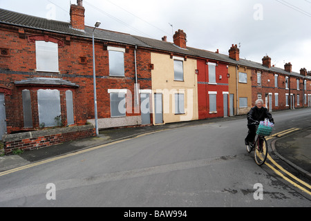 Eine ältere Frau Zyklen vorbei an heruntergekommenen Häusern bereit für den Abriss, Goole in der Nähe von Hull UK Stockfoto