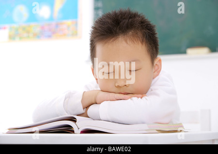 Junge beim Einschlafen an seinem Schreibtisch im Klassenzimmer Stockfoto