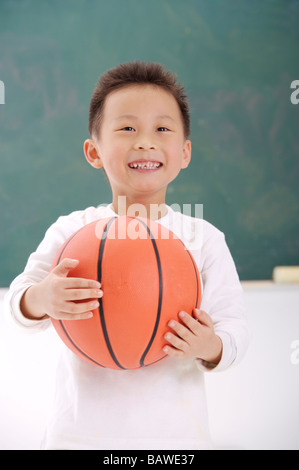 Junge stand vor Tafel hält einen basketball Stockfoto