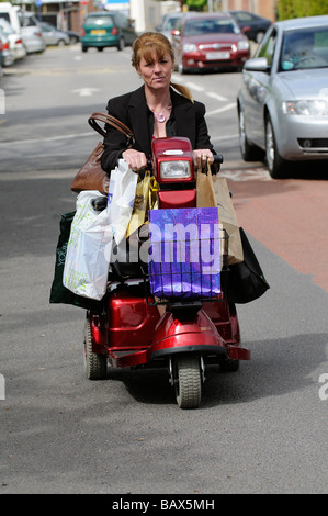 Frauen fahren Mobilität Roller beladen mit ihr Einkaufen in Tragetaschen Stockfoto