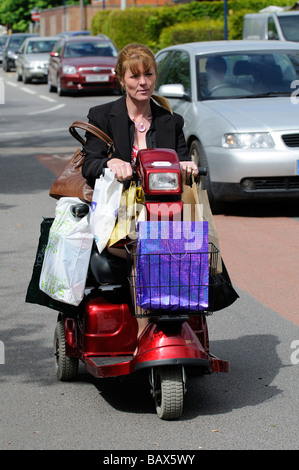 Frauen fahren Mobilität Roller beladen mit ihr Einkaufen in Tragetaschen Stockfoto