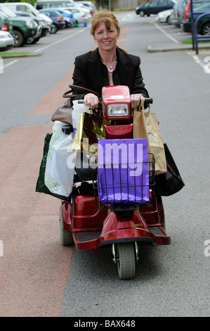 Frau sitzend auf einem Rascal Mobilität Scooter zusammen mit ihr Einkaufen fahren Stockfoto