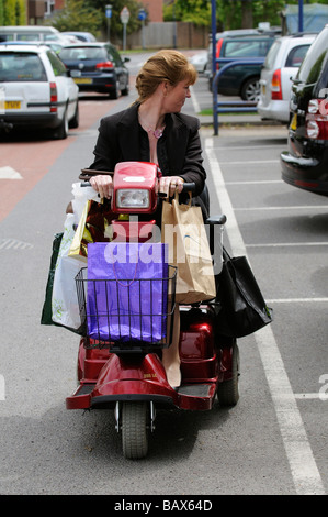 Frau sitzend auf einem Rascal Mobilität Scooter entlang fahren in umgekehrter Reihenfolge Stockfoto