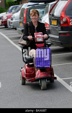 Frau sitzend auf einem Rascal Mobilität Scooter fahren entlang Stockfoto