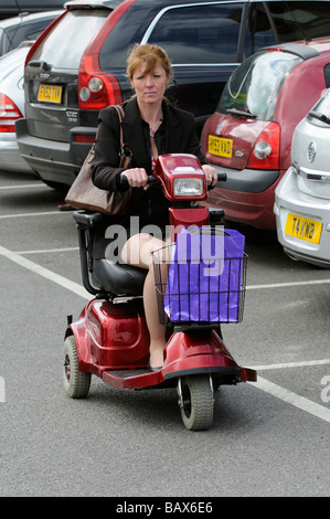 Frau sitzend auf einem Rascal Mobilität Scooter fahren entlang Stockfoto