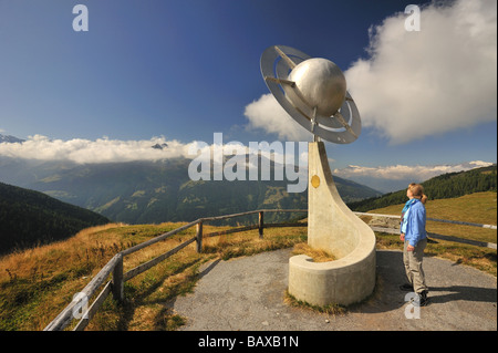 Eine Frau Wanderer bewundert eine Skulptur, die Saturn auf dem Planeten-Wanderweg (Sentier des Planetes) in den Schweizer Alpen. Stockfoto