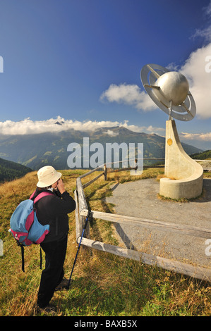 Ein Wanderer Frau fotografiert eine Skulptur, die Saturn auf dem Planeten-Wanderweg (Sentier des Planetes) in den Schweizer Alpen. Stockfoto