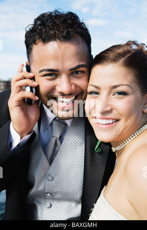 Multi-ethnische Braut und Bräutigam mit Handy Stockfoto
