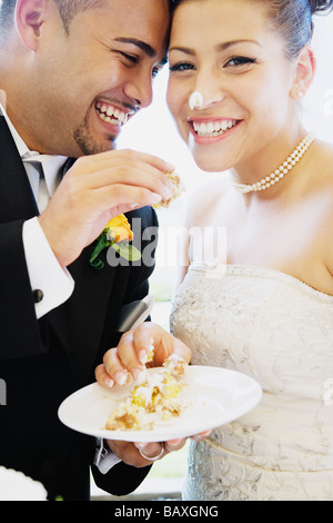 Multi-ethnische Braut und Bräutigam Kuchen essen Stockfoto