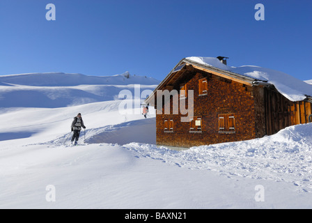 Skifahrer, die Ankunft im verschneiten Almhütte, reichen Schwarzwassertal, Kleinwalsertal, Allgäu, Allgäu, Vorarlberg, Österreich Stockfoto