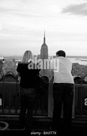 Ein paar auf der Oberseite der Rock Aussichtsplattform Rockefeller Center in New York mit Blick auf das Empire State Building. Stockfoto