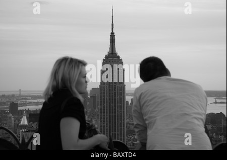 Ein paar auf der Oberseite der Rock Aussichtsplattform Rockefeller Center in New York mit Blick auf das Empire State Building. Stockfoto