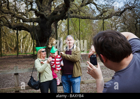 Touristen posiert in 'Robin Hood' Hüte für ein Familienfoto an der Major Oak, Sherwood Forest, Nottinghamshire. Stockfoto