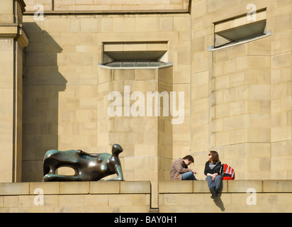 Menschen, die Entspannung außerhalb Leeds Art Gallery, neben Moores Skulptur liegende Frau, West Yorkshire, England UK Stockfoto