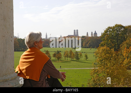 Frau mit Blick auf den englischen Garten und die Türme der Theatinerkirche und Frauenkirche, München, Bayern, Deutschland Stockfoto