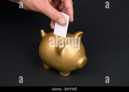 Ein Mann legt einen Zettel in ein Sparschwein mit Textfreiraum Stockfoto