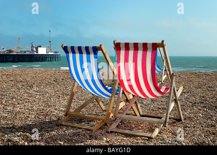 Zwei Liegestühle am Strand mit Brighton Pier im Hintergrund Stockfoto