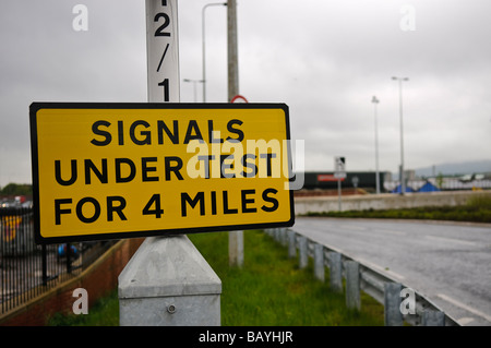 Der Schild 'Signale unter Test für 4 Warnung Treiber Miles', die neue Straße Hinweisschilder sind unter Test, gegen bewölkten Himmel und Wolken Stockfoto
