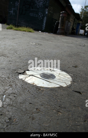eine alte beschädigte cd Compcat Disk auf Fahrbahn Stockfoto