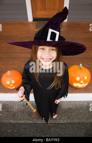 Gemischte Rassen junges Mädchen im Hexenkostüm mit Halloween-Kürbisse Stockfoto