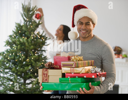 Afrikanische amerikanische Mann, hält Weihnachtsgeschenke von Baum Stockfoto