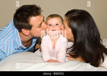 Horizontale Nahaufnahme Portrait ein sechs Monate altes Baby und Eltern stolz auf die Wange küssen Stockfoto