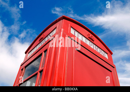 Eine ikonische rote britische Telefonzelle kontrastierte mit einem blauen Himmel und weißen Wolken Stockfoto