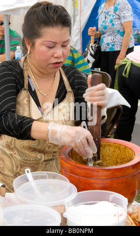 Frau bereitet eine Hmong asiatische Spezialitäten in einem Mörser und Stößel. Hmong Sport Festival McMurray Feld St Paul Minnesota USA Stockfoto