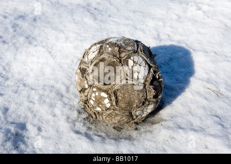 worn-out Fußball auf Schnee Stockfoto