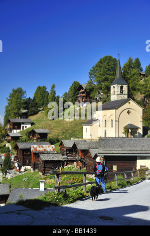 Eine Ansicht von Chandolin mit seiner Kirche. Zwei Wanderer die Aussicht bewundern. Stockfoto