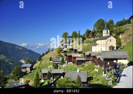 Eine Ansicht von Chandolin mit seiner Kirche. Zwei Wanderer die Aussicht bewundern. Stockfoto