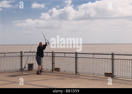 Ein Mann Angeln aus dem Ende des Southwold Pier in Southwold, Suffolk, Uk Stockfoto