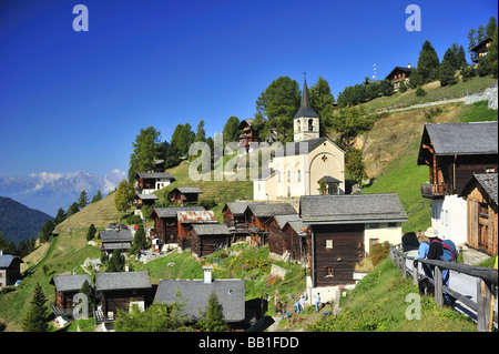 Eine Ansicht von Chandolin mit seiner Kirche. Zwei Wanderer die Aussicht bewundern. Stockfoto