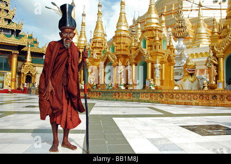 MYANMAR, Yangon. Alten burmesischen buddhistischer Mönch tragen traditionelle rote Kleidung, seine alm-Schale auf dem Kopf tragen Stockfoto